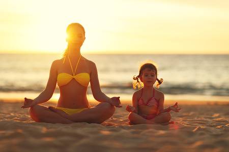 75486172-madre-e-hija-familia-feliz-niño-hacer-yoga-meditar-en-posición-de-loto-en-la-playa-al-atardecer